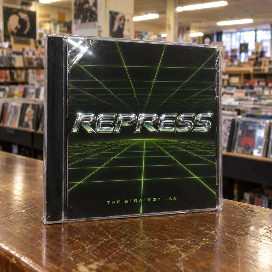 A CD in its jewel case on a record store counter: black rave cover with a green laser grid, titled Repress