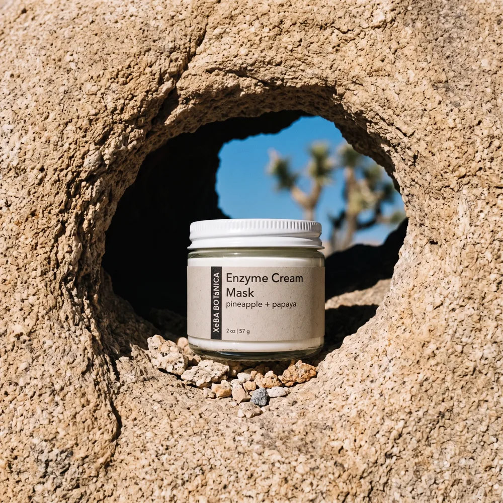 Xēba Botánica album cover: the Enzyme Cream Mask in a granite hollow with a Joshua tree beyond